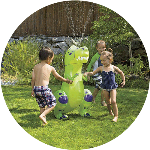 Three kids playing outside around an inflatable dinosaur sprinkler buddy.